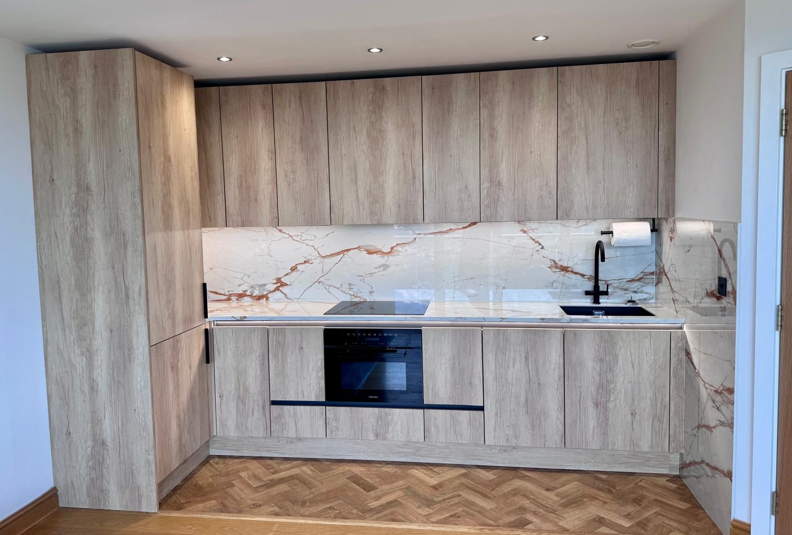 Full-height timber-look kitchen cabinetry and a pale veined splashback